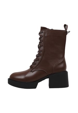 Bota de piel marrón con cordones hasta el tobillo, lengüeta para tirar, tacón grueso negro y suela con plataforma.