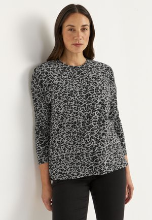 Grå langærmet top med sort leopardmønster, rund halsudskæring og afslappet pasform. Båret med sorte bukser.