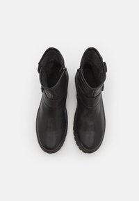 Botas de tobillo de piel negra con forro de felpa texturizada, que cuentan con un cierre lateral y un diseño de puntera redonda. Suela rígida de goma que proporciona tracción.