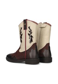 Bottes de cheville de style occidental avec un design bicolore en cuir crème et marron. Des découpes notables et des textures contrastées améliorent l'intérêt visuel.