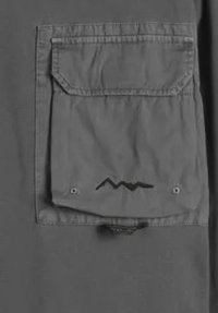 Tasca quadrata in tessuto con pattina e očh ruchya, caratterizzata da un piccolo motivo a zigzag vicino al centro inferiore della tasca.