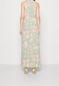 Kukallinen maksimekko vaaleanvihreällä pohjalla, jossa on vaaleanpunaisia ja valkoisia ruusukuvioita. Ominaisuuksia ovat kaula-aukkoinen malli ja avainaukko selässä.