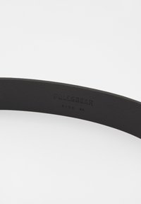 Cintura in pelle nera con una superficie liscia, con il marchio "Pull&Bear" impresso e la taglia "85" segnato all'interno.