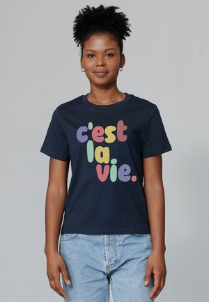 T-shirt en coton marine arborant le texte multicolore "c'est la vie" dans différentes polices ludiques. Manches courtes, col rond classique, coupe décontractée.