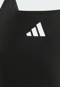 Svart sport BH med glatt stoff tekstur, med en hvit Adidas-logo i tre diagonale striper på øvre venstre side.