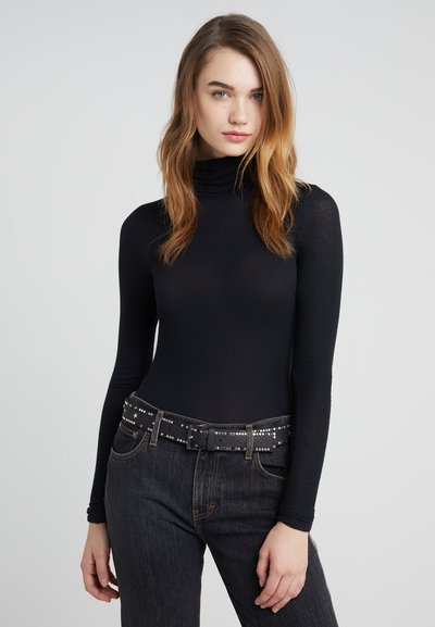 Musty pikkade varrukatega mock neck topp, mis on valmistatud kergetest kangast, koos tumedate teksade ja musta nurgelise vööga, millel on hõbedased aktsendid.