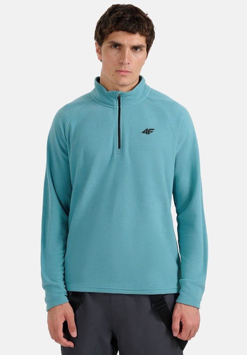 Pull-over en polaire bleu clair avec col zippé jusqu'à mi-hauteur. Comprend un logo sur la poitrine et des manches longues, fabriqué en tissu doux et texturé.