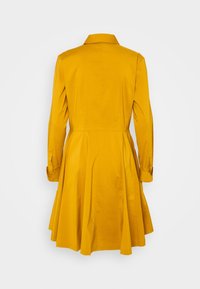 Żółta bawełniana sukienka z dopasowanym topem, rozkloszowanym dołem, długimi rękawami, wykładanym kołnierzykiem i mankietami zapinanymi na guziki. Gładka faktura z minimalnymi detalami.