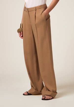 Wide-leg trousers in a light brown, textured fabric. Features a high waist with pleats, side pockets, and a relaxed fit.