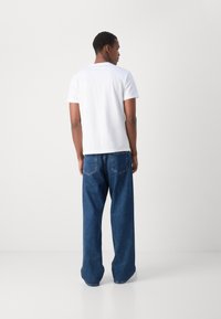 Hvid t-shirt med korte ærmer, kombineret med løstsiddende jeans i mellemblå denim. Enkelt design med minimale syninger.