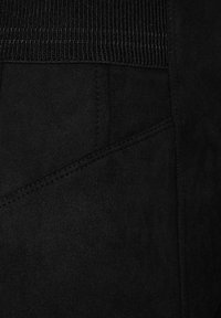 Tessuto nero caratterizzato da una superficie liscia e un'area in vita a coste. La cucitura aggiunge dettaglio con linee di cucitura inclinate visibili sui lati.