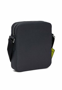 Borsa a tracolla nera con superficie texturizzata, chiusura con zip, tracolla regolabile e un dettaglio etichetta verde a contrasto.