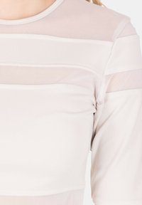 Top a maniche corte grigio chiaro con pannelli trasparenti sovrapposti e scollo rotondo. Texture liscia con motivi a strisce orizzontali.