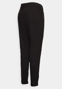Pantalon noir fuselé avec taille élastique et poche arrière, vu de dos sur fond blanc.