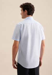 Camicia azzurra a maniche corte con colletto ripiegato, texture liscia e orlo arrotondato, vista dal retro.