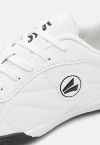 Baskets blanches en cuir synthétique texturé, avec des accents et un logo noirs, conçu à lacets et doté d'une semelle en caoutchouc.