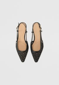 Ballerines à bride arrière pointues noires avec motif géométrique texturé et semelles intérieures rembourrées couleur tan sur un fond clair uni.