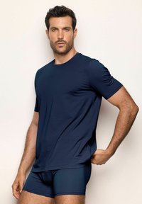 T-shirt à manches courtes bleu marine en tissu lisse, associé à un short ajusté assorti. Design simple à col rond avec un minimum de détails.