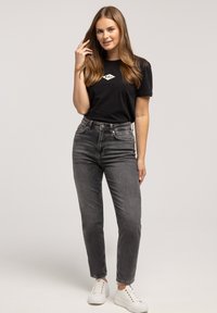 Czarny t-shirt z diamentowym logo, szare dżinsy z wysokim stanem oraz białe trampki. Gładka tkanina, dopasowany krój i casualowy design.