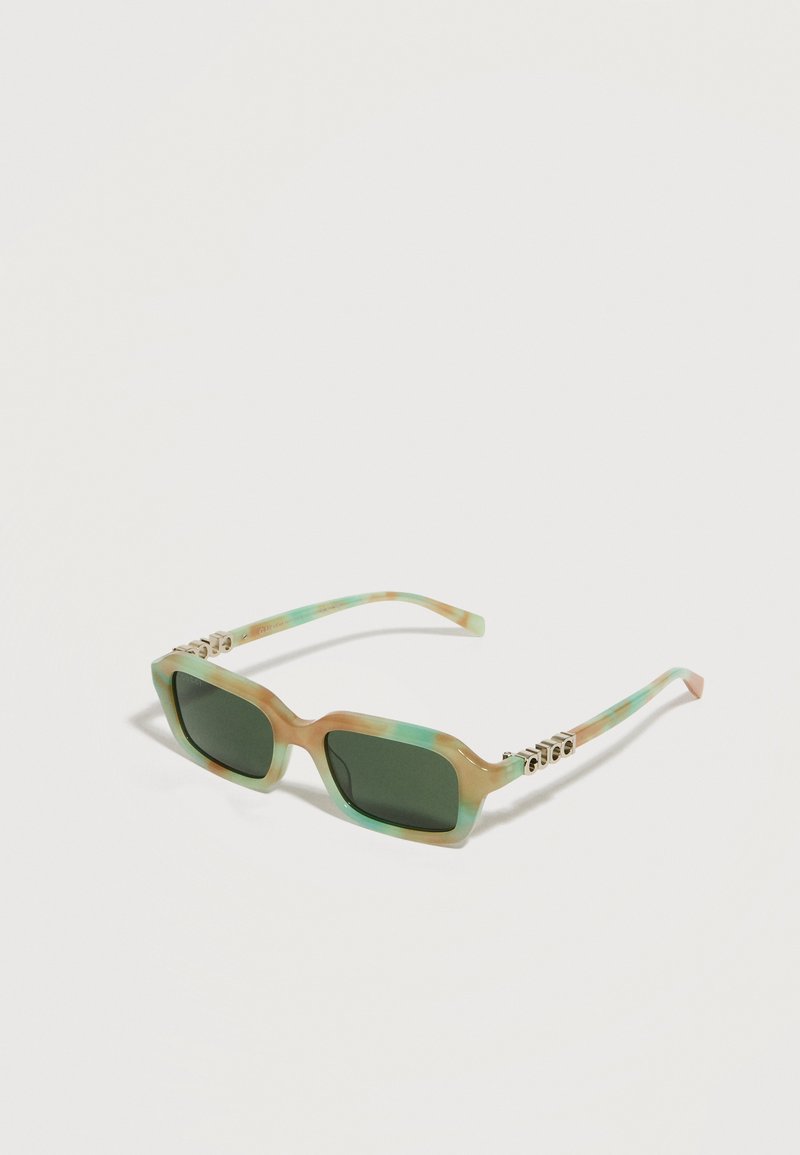 Lunettes de soleil rectangulaires avec des verres teintés verts et des montures marbrées beige et turquoise reposant sur une surface blanche.