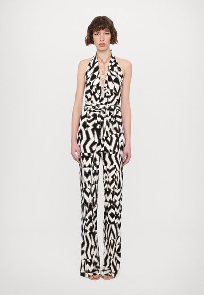 Zwart-wit gestreepte jumpsuit met halternek, knoop in de taille en wijde pijpen, met een abstract zigzagpatroon.