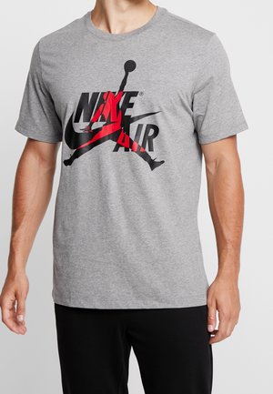 Szara koszulka z krótkim rękawem z czerwoną i czarną grafiką logo Nike Air z przodu. Wykonana z miękkiej bawełny, z okrągłym dekoltem.