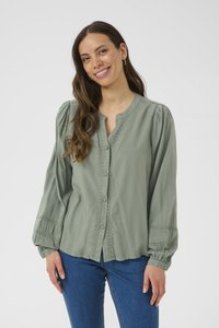 Blusa verde chiaro con bottoni, scollo rotondo, maniche plissettate e dettagli in pizzo. Realizzata in un tessuto morbido e liscio.