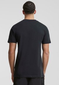 Svart bomulls-T-skjorte med korte ermer og rund hals. Har en jevn tekstur, enkel design, og ingen synlige grafikker eller mønstre.