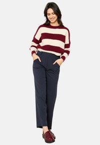 Bordeaux en crèmekleurige gestreepte gebreide trui gecombineerd met marineblauwe gestreepte broek en bordeaux kleurige loafers, met zakken en een relaxed fit.