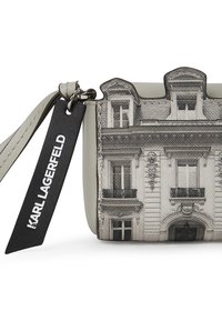Szürke bőr táska nyomtatott építészeti mintával, lekerekített tetejű, fekete címkével, amelyen fehér betűkkel szerepel a "Karl Lagerfeld" felirat.