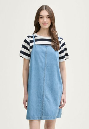 Jeansjurk met verstelbare bandjes, lichtblauwe kleur, eenvoudige A-lijn vorm, met een centrale naad en zijzakken. Gestreept T-shirt eronder.