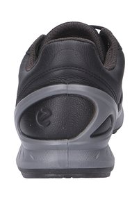 Scarpe sportive nere con tomaia in pelle, suola in gomma grigia, colletto imbottito e dettagli intagliati sul tallone.