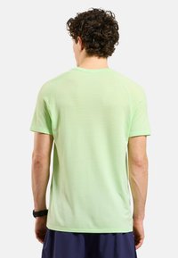 Groene sportieve shirt met korte mouwen en een mesh-textuur, met raglanmouwen en een ronde halsontwerp. Eenvoudige achterkant.