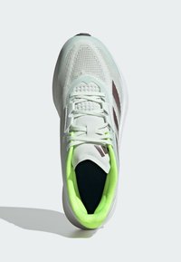 Scarpa sportiva bianca con una tomaia in rete traspirante, fodera interna verde e dettagli laterali marroni. Presenta un colletto imbottito e lacci.