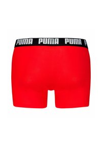 Calzoncillos rojos con una cinturilla elástica negra que presenta el logotipo repetido de "PUMA" en blanco. Tela suave y forma ajustada.