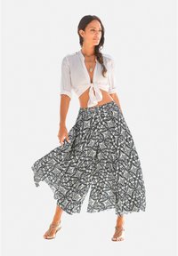 Witte knoopbloes met voorzijde en vloeiende zwart-witte, patroon rok. Rok heeft ingewikkelde, draainde ontwerpen. Draagt het met zilveren sandalen.