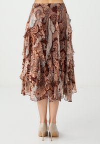 Bruine gelaagde rok met een paisleypatroon in tinten van crème en blauw. Licht, luchtig stof met ruffles langs de zoom. Elegante design.