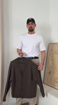 Barna kötött kardigán V-nyakkal, elülső gombolással és hosszú ujjakkal. Egy vállfára akasztva, semleges háttér előtt bemutatva.