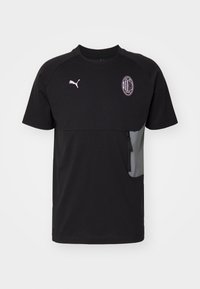 Camiseta negra de manga corta hecha de un material liviano. Presenta un bolsillo gris en el frente y un logo rosa en el pecho.