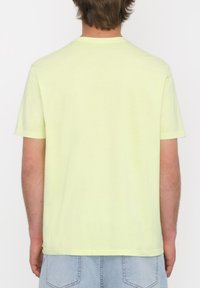 Camisa de tirantes cortos, con cuello redondo, en amarillo claro, hecha de suave algodón, con un corte recto y un diseño liso en la parte posterior.