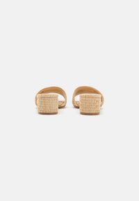 Beiga vävda slide-sandaler med öppen baksida, tjock vävd klack och slät innersula; minimalistisk design, naturlig textur och neutral färg.