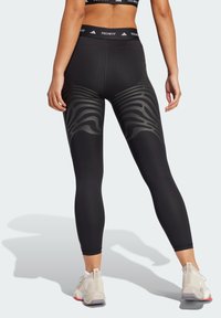 Leggings de sport noirs avec un motif gris texturé et ondulé au niveau des mollets et une taille unie arborant le branding "TECHFIT".