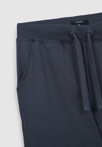 Ciemnoniebieskie dresy wykonane z miękkiej bawełnianej mieszanki. Posiadają ribbowany pas w talii, regulowane sznurki i boczne kieszenie.