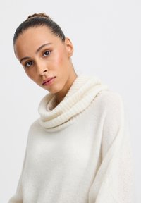 Pull à col bénitier de couleur crème, avec un tricot doux et texturé. La coupe décontractée tombe librement avec une silhouette cosy et confortable.