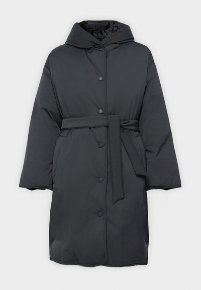 Melnā pildītā jaka ar kapuci, apkakles jostas un pogām ar nospiest. Iezīmē gludu tekstūru un platām piedurknēm, lai nodrošinātu brīvu piegulšanu.