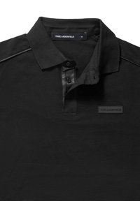 Polo noir Karl Lagerfeld avec col replié, patte de boutonnage et une petite écusson logo sur la poitrine.