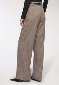 Pantaloni con un motivo a quadri marrone, design a gamba larga, con una cintura nera in vita e una finitura in tessuto testurizzato.