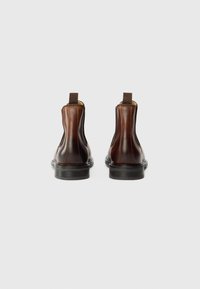 Brown leather ankle boots with elastic side panels, flat black soles, and pull tabs for easy wear. Smooth texture with visible stitching.