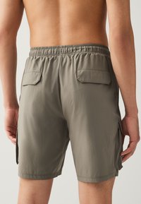 Shorts cargo pour hommes en tissu gris clair avec une ceinture élastique, deux poches arrière et une coupe droite.