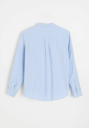 Jasnoniebieska koszula z długim rękawem z białymi pionowymi paskami, zapinanymi mankietami i plisą z tyłu, pokazana od tyłu na białym tle.